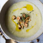 Parsnip Soup with hazelnuts, cardamom and thyme. A simple soup that can be made on the stovetop or roasted in the oven. Vegan Adaptable. #parsnipsoup #parsniprecipes #parsnips