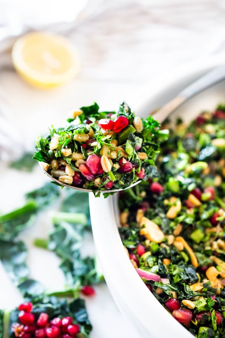 Kale Farro Salad with Almonds and Pomegranate Seeds. Think of this like a Winter Tabbouleh- lemony light and flavorful, this easy Middle Eastern-inspired salad can be made ahead, perfect for mid-week lunches. #healthykalesalad #kalesalad #vegansalad #vegankalesalad #farrosalad #tabouli #tabbouleh