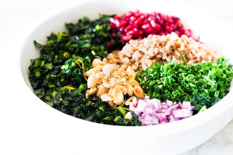 Healthy Vegan Kale Farro Salad with Almonds and Pomegranate Seeds. Think of this like a Winter Tabbouleh- lemony light and flavorful, this easy Middle Eastern-inspired salad can be made ahead, perfect for mid-week lunches. #healthykalesalad #kalesalad #vegansalad #vegankalesalad #farrosalad #tabouli #tabbouleh