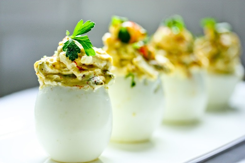 A simple delicious recipe for the Best EVER Deviled Eggs- Made with crumbled bacon, cheddar and onion. | www.feastingathome.com
