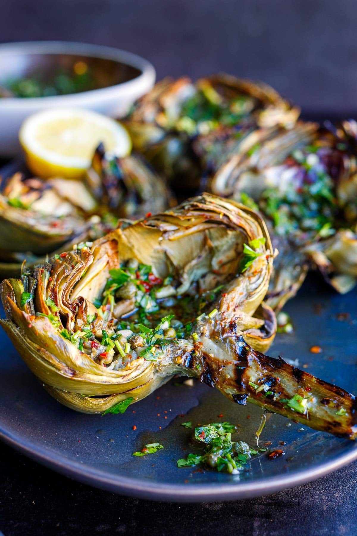 grilled artichokes on plate with Italian salsa verde on top.