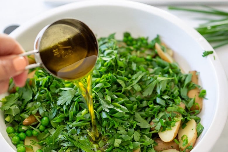 adding olive oil to the salad