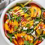 This summery peach salad recipe is made with fresh peaches, arugula, creamy goat cheese, slivered almonds, and basil tossed in a vinaigrette.