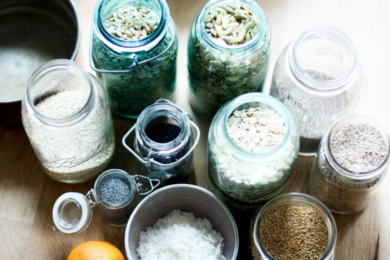 ingredients in glass jars for easy homemade granola recipe- nuts, seeds, oats, coconut.