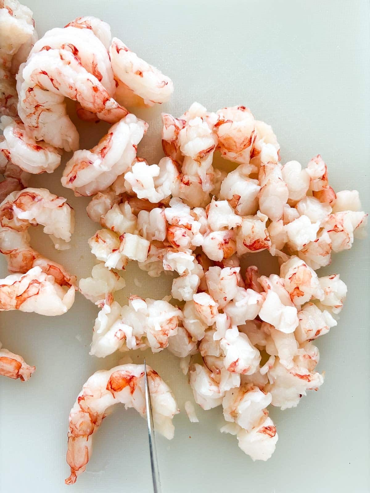 knife cutting shrimp into half-inch pieces.