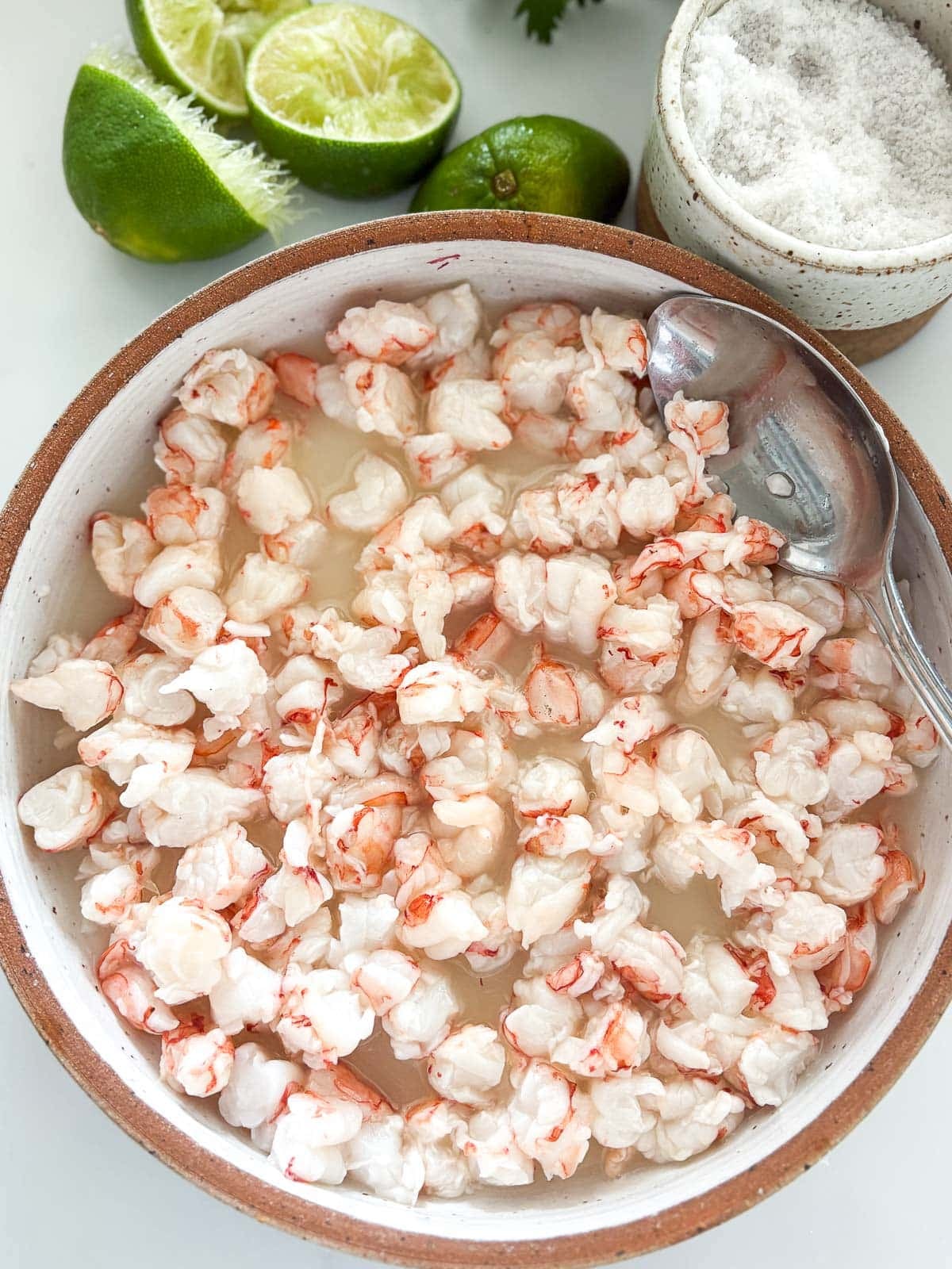 chopped shrimp pieces curing in lime juice in a wide, shallow bowl. 
