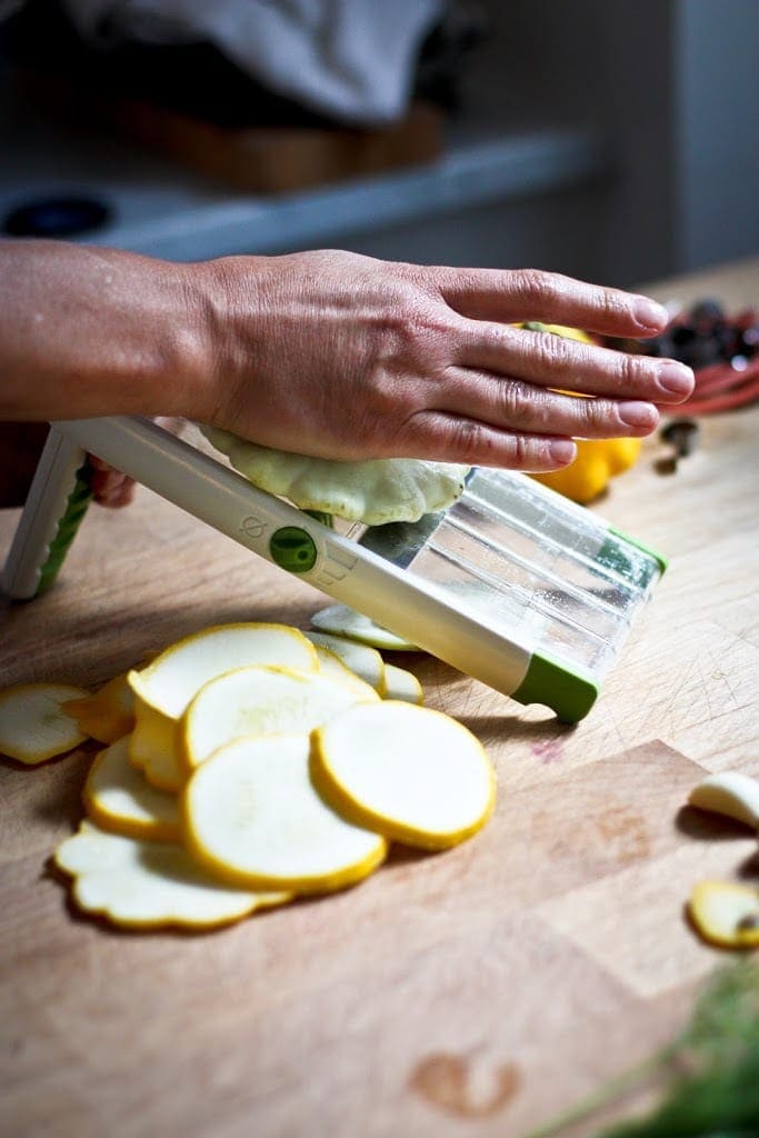 slicing zucchini on a mandolin.