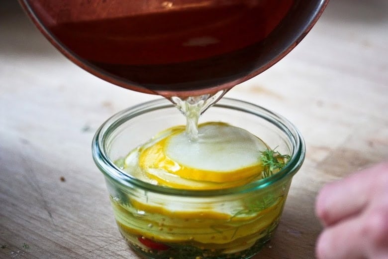 pouring the brine over the zucchini in a jar.