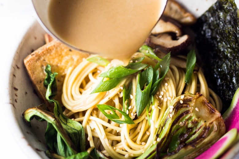 Pouring the broth over the noodles, veggies and tofu. 