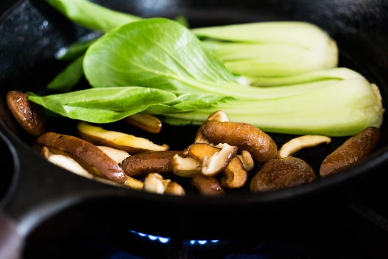 bok chow and shiitakes sautéing in a pan