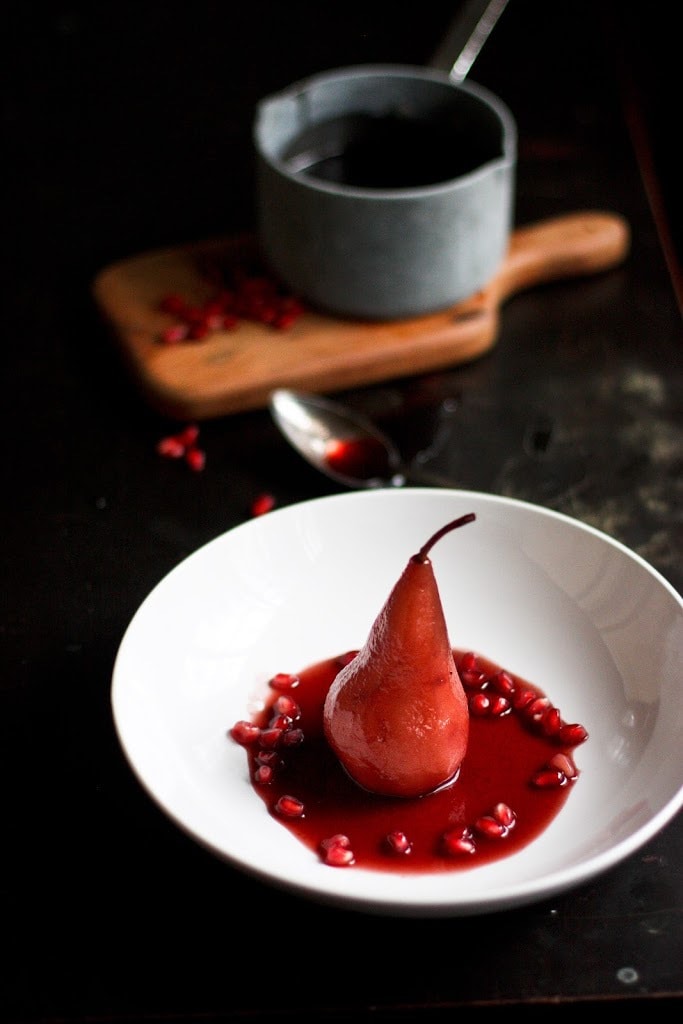 Poached pears get a little makeover with red wine, pomegranate seeds &. cardamom. This easy healthy dessert is perfect after a heavy holiday meal and is a snap to make! #poachedpears