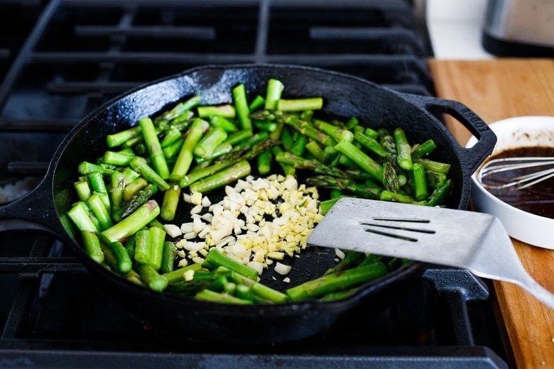 stir-frying asparagus, adding garlic and ginger to the pan
