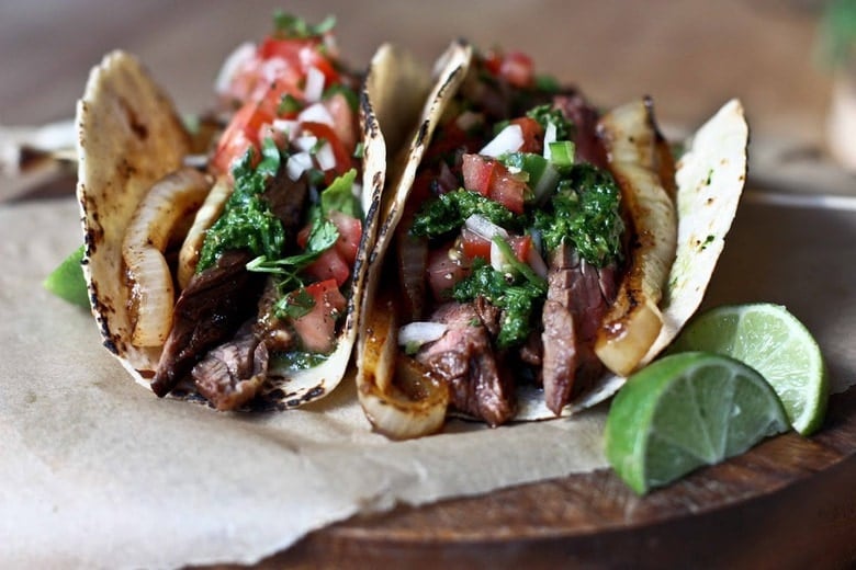 Two Steak Tacos with all the toppings on parchment paper