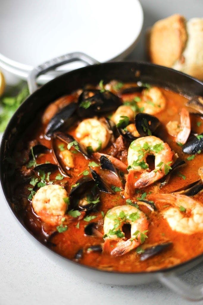 Summer Seafood Stew in a light and flavorful tomato-fennel broth with smoky chorizo. Serve with Crusty Bread to mop up all the flavorful juices! #bouillabaisse #fishstew #seafoodstew #stew #cioppino #seafood #fish #fishsoup #seafoodsoup 