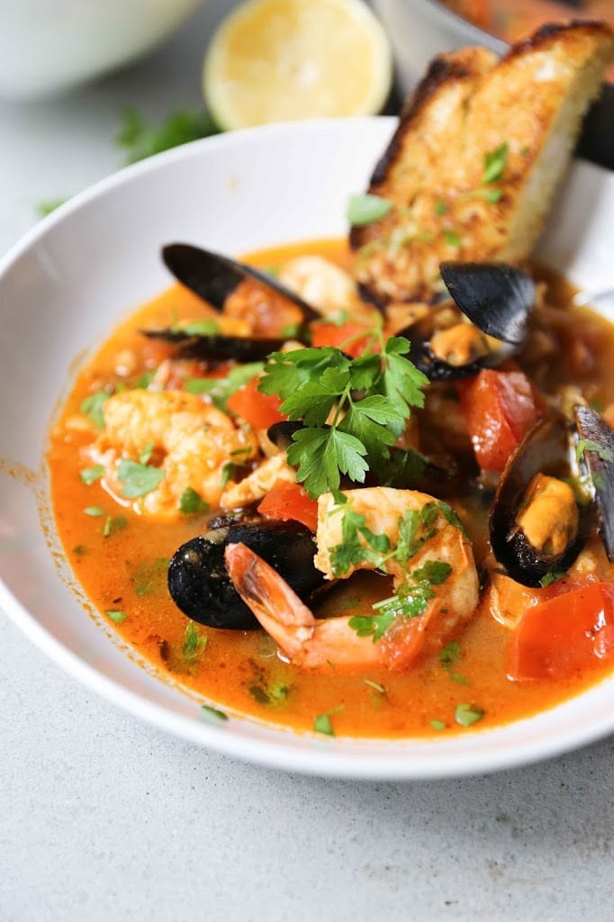 Summer Seafood Stew in a light and flavorful tomato-fennel broth with smoky chorizo. Serve with Crusty Bread to mop up all the flavorful juices! #bouillabaisse #fishstew #seafoodstew #stew #cioppino #seafood #fish #fishsoup #seafoodsoup 