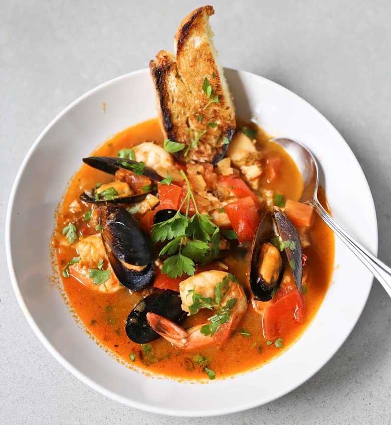 Summer Seafood Stew in a light and flavorful tomato-fennel broth with smoky chorizo. Serve with Crusty Bread to mop up all the flavorful juices! #bouillabaisse #fishstew #seafoodstew #stew #cioppino #seafood #fish #fishsoup #seafoodsoup 