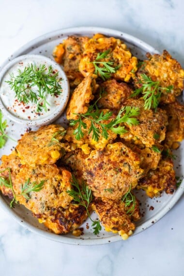 Celebrate the bounty of summer with fresh Corn Fritters! A flavorful recipe that works as a tasty appetizer, hearty side dish, or a vegetarian main course. Serve with creamy Cilantro Sauce!