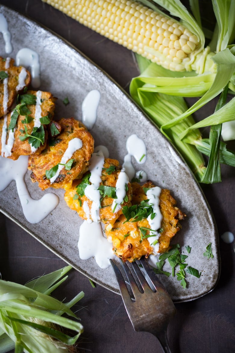 Spicy Corn Fritters with Cilantro Cream - an easy delicious recipe that works as an appetizer or vegetarian main! www.feastingathome.com #cornfritters #corncakes