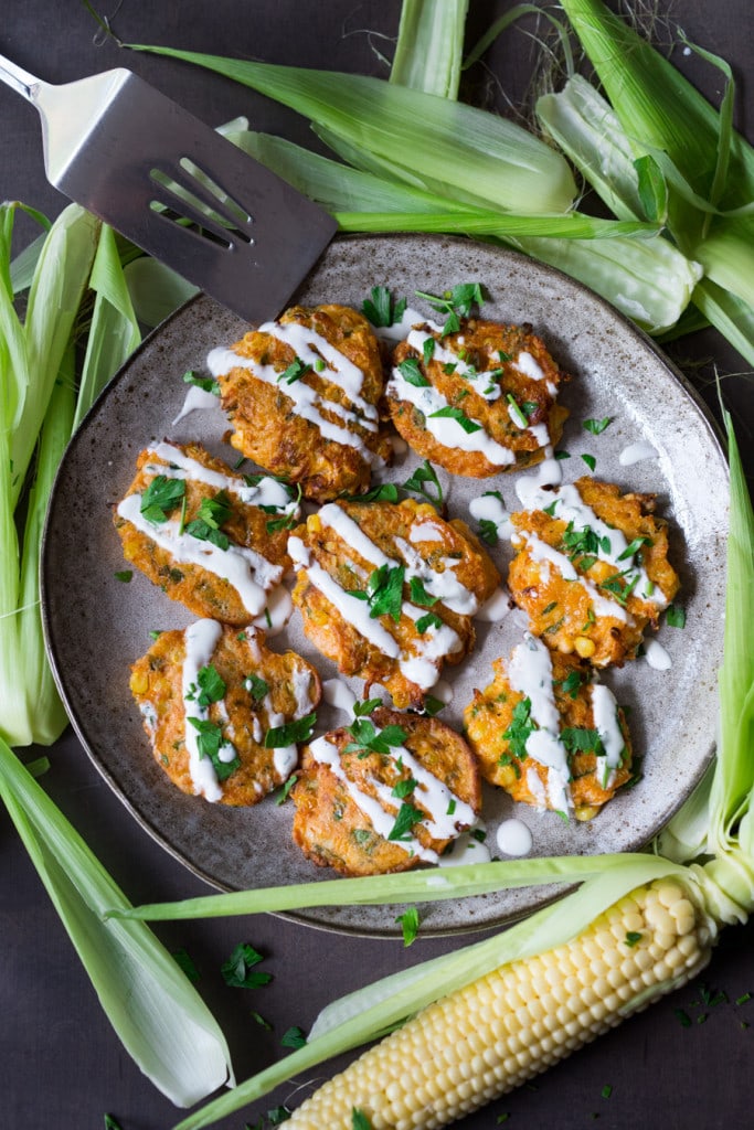 Spicy Corn Fritters with Cilantro Cream - an easy delicious recipe that works as an appetizer or vegetarian main! www.feastingathome.com #cornfritters #corncakes