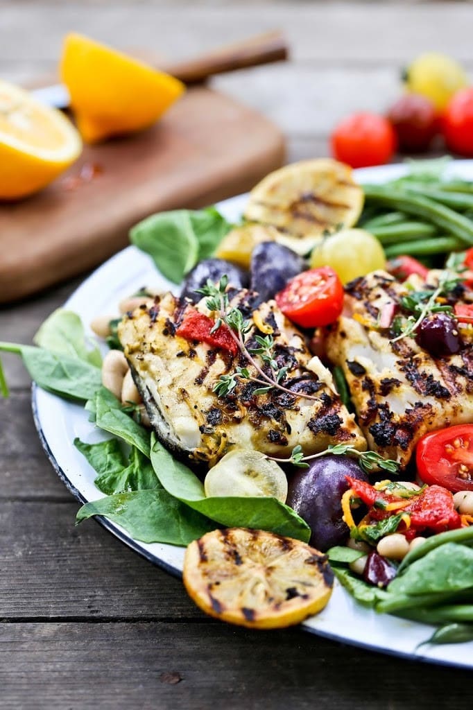Nicoise salad with grilled fish, tomatoes, purple potatoes, fresh thyme, and spinach.