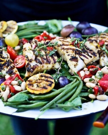 This grilled fish salad is a fresh Mediterranean-inspired dinner made with grilled fish, potatoes, green beans, olives, and a bright lemon Niçoise dressing.