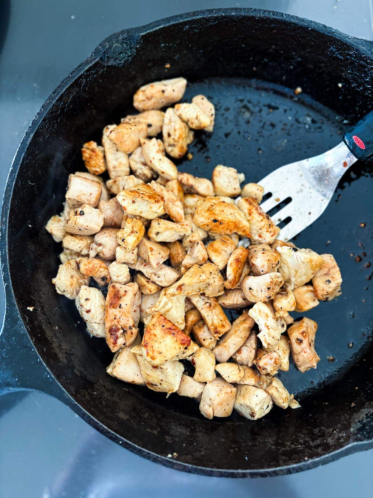 Browning bite-sized pieces of chicken in a skillet with salt, pepper and olive oil.