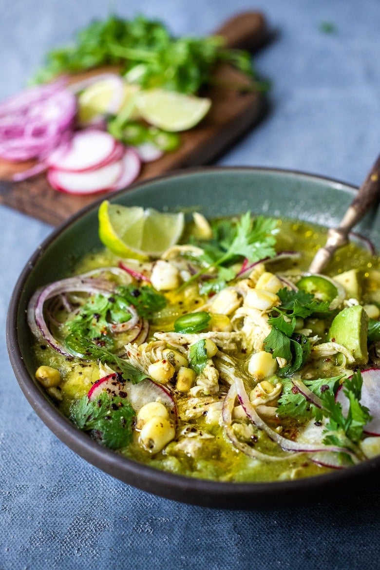 A delicious recipe for Pozole Verde- a flavorful Mexican stew made with tomatillos, green chilies, chicken and hominy, topped with cilantro, avocado and red onions. #pozole 