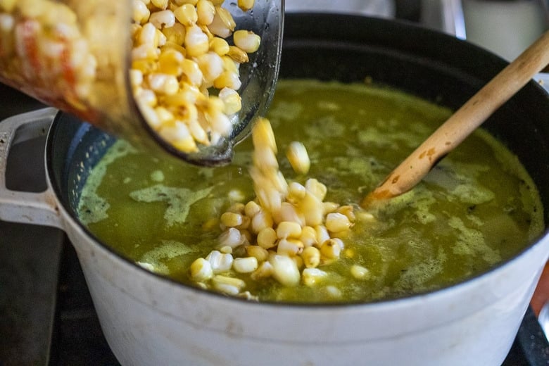 pouring the hominy into the soup