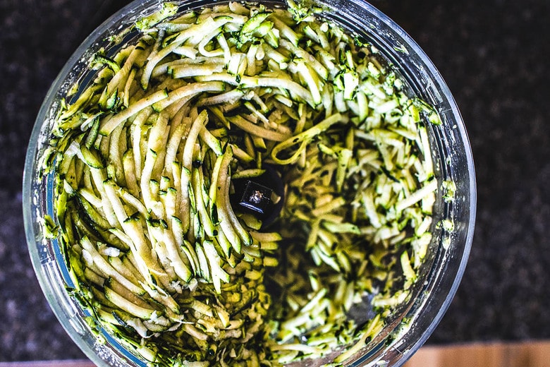 grated zucchini in bowl of food processor.