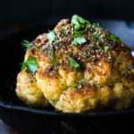 Whole Roasted Cauliflower with Zaatar Spice and Tahini Sauce- a healthy vegan side dish bursting with Middle Eastern flavor. Easy and delicious! #roastedcauliflower #cauliflower #veganside #tahinisauce #zaatar #tahinicauliflower