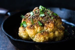 Whole Roasted Cauliflower with Zaatar Spice and Tahini Sauce- a healthy vegan side dish bursting with Middle Eastern flavor. Easy and delicious! #roastedcauliflower #cauliflower #veganside #tahinisauce #zaatar #tahinicauliflower