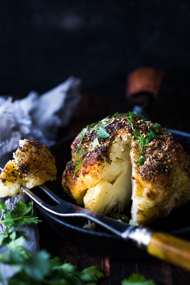 Whole Roasted Cauliflower with Zaatar Spice and Tahini Sauce- a healthy vegan side dish bursting with Middle Eastern flavor. Easy and delicious! #roastedcauliflower #cauliflower #veganside #tahinisauce #zaatar #tahinicauliflower