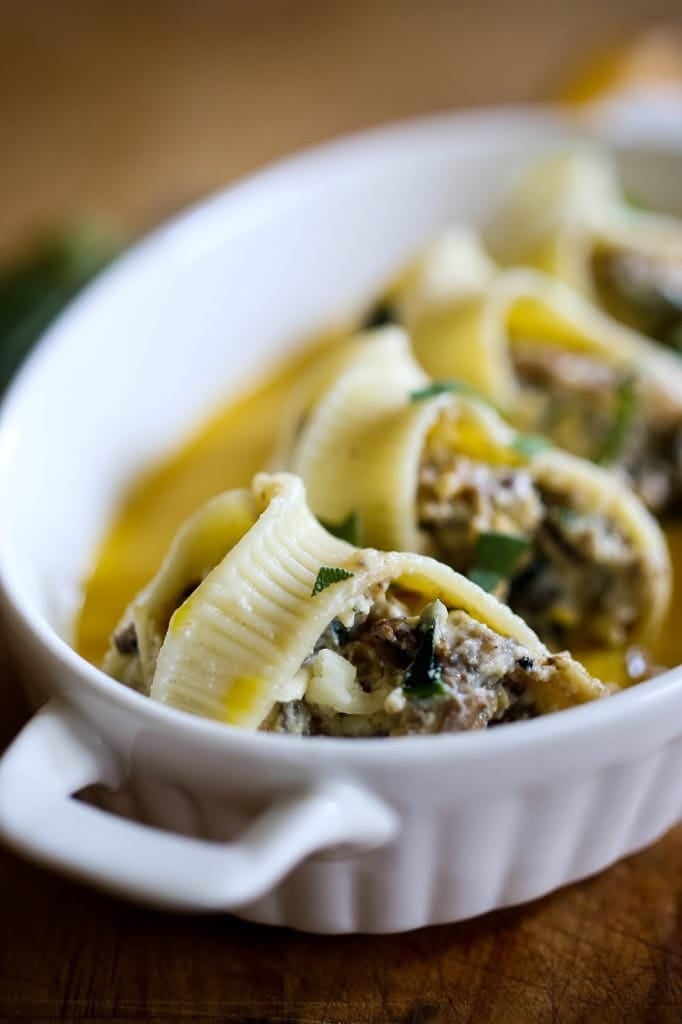 A delicious recipe for stuffed shells with pumpkin sauce, with Italian sausage (or substitute mushrooms) and a creamy flavorful Pumpkin parmesan sauce. | www.feastingathome.com