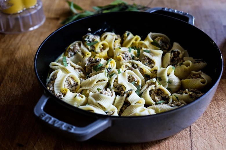 A delicious recipe for stuffed shells with pumpkin sauce, with Italian sausage (or substitute mushrooms) and a creamy flavorful Pumpkin parmesan sauce. | www.feastingathome.com