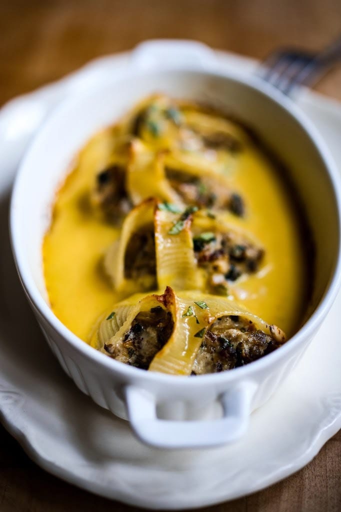 A delicious recipe for stuffed shells with pumpkin sauce, with Italian sausage (or substitute mushrooms) and a creamy flavorful Pumpkin parmesan sauce. | www.feastingathome.com