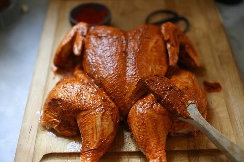 chicken, slathered with peri peri marinade on a cutting board