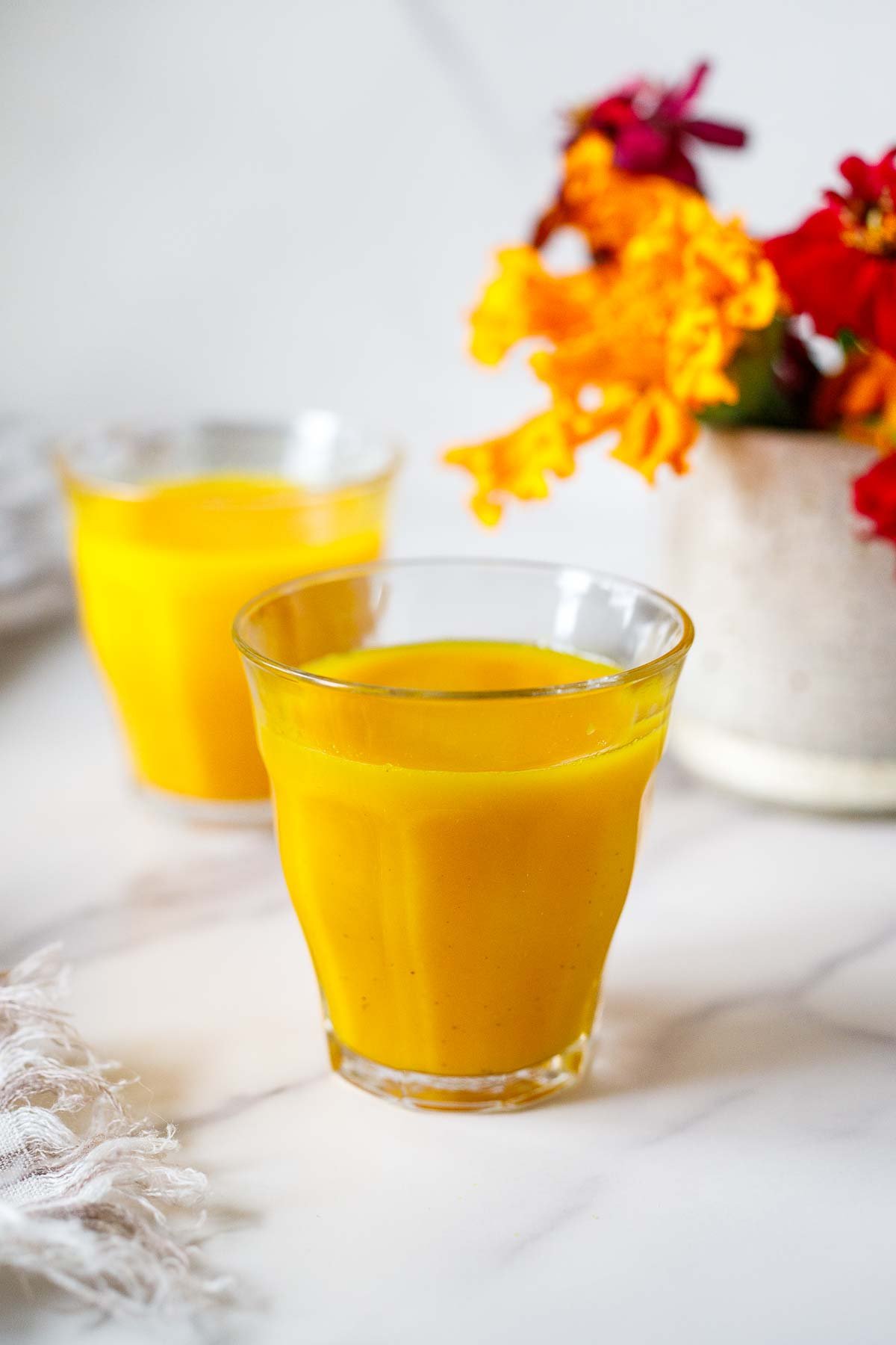 two shot glasses filling with ginger turmeric juice.