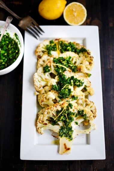 This Roasted Cauliflower Steak Recipe is topped with an herby zesty green sauce called Gremolata. A delicious vegan dinner idea!