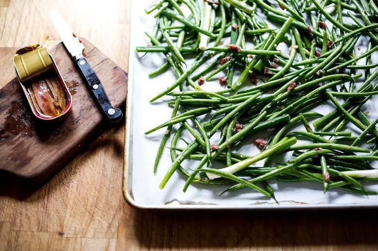 Charred Green Beans with Bagna Cauda- an Itailian Marinade with olive oil, anchovies, garlic and chili flakes. Roasted in the oven with scallions and lemon zest, these green beans are full of umami flavor. | www.feastingathome.com 