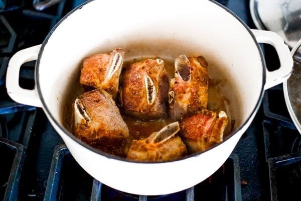 beef short ribs searing and browning in a dutch oven.