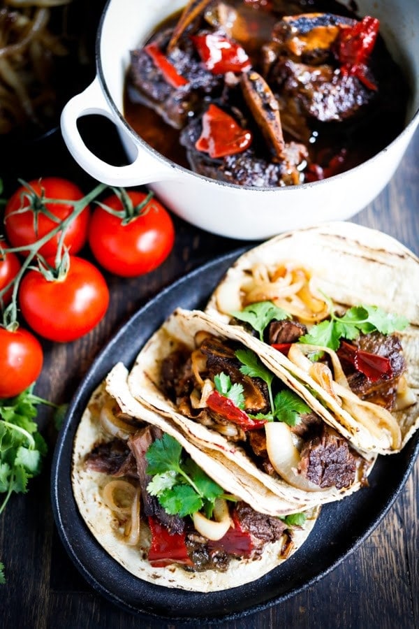 plate of three mexican short rib tacos garnished with cilantro.