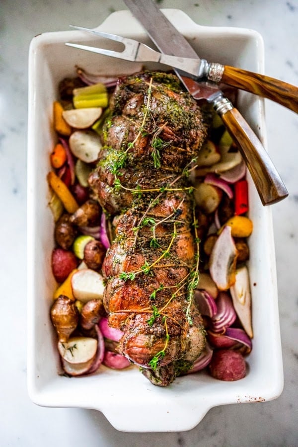 How to make the most delicious, Slow-Roasted Leg of Lamb with boneless lamb and a flavorful herb crust and filling,  roasted over vegetables and served with Mint Gremolata.  A special dinner is worthy of your holiday table.  #legoflamb #lamb #lambleg #easterdinner #easter #stuffedlamb #lambrecipes #lambroast #roastlegoflamb 