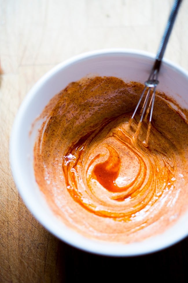 harissa aioli in a bowl with a mini whisk