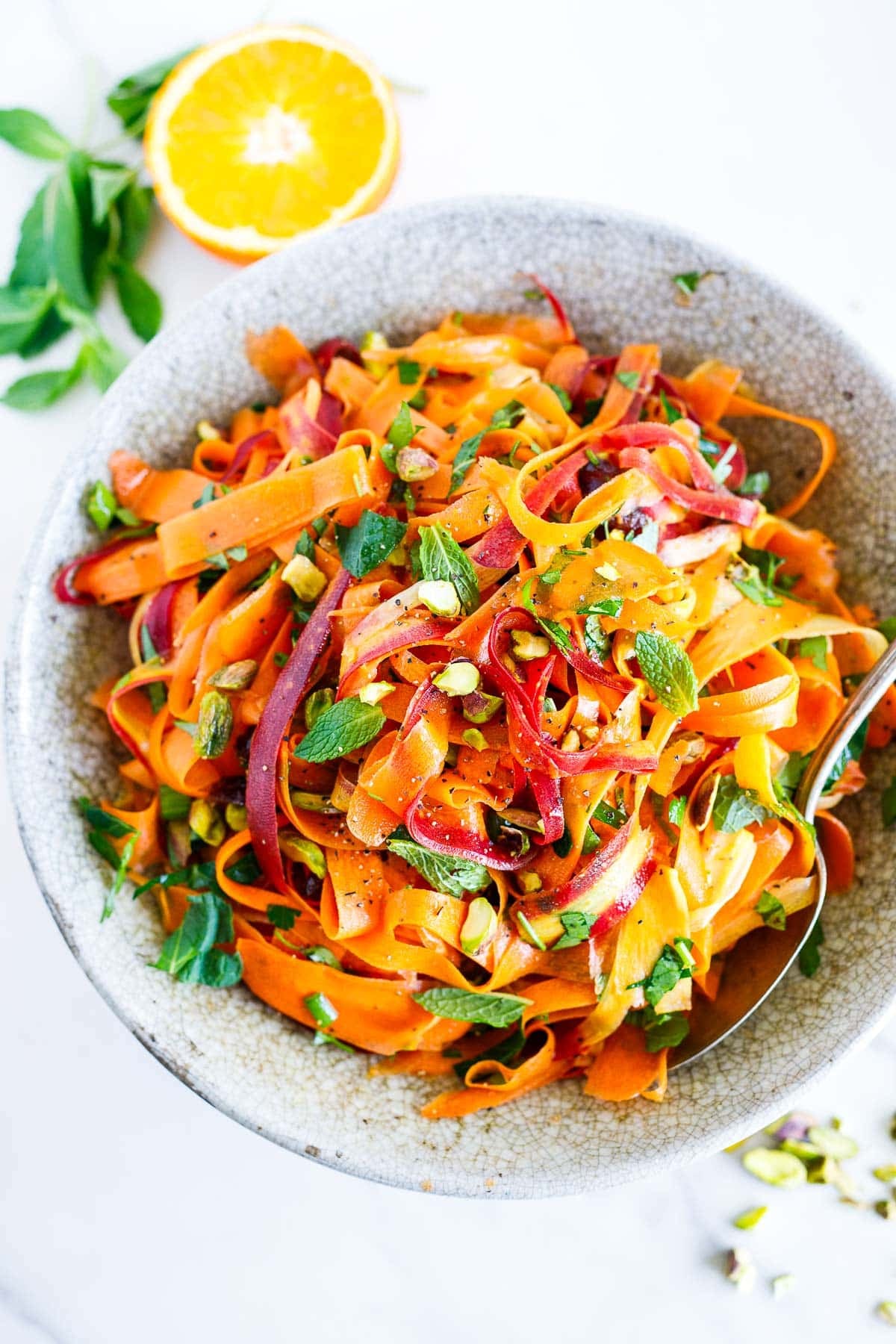 This Moroccan carrot salad is a light and refreshing side dish. Made with fresh carrots, herbs, pistachio nuts, dates, and an orange-cumin dressing. Vegan.