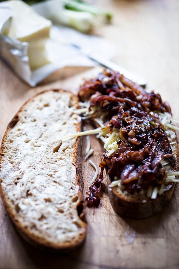 two slices of bread - one with butter, the other with grated gruyere cheese and caramelized onions.