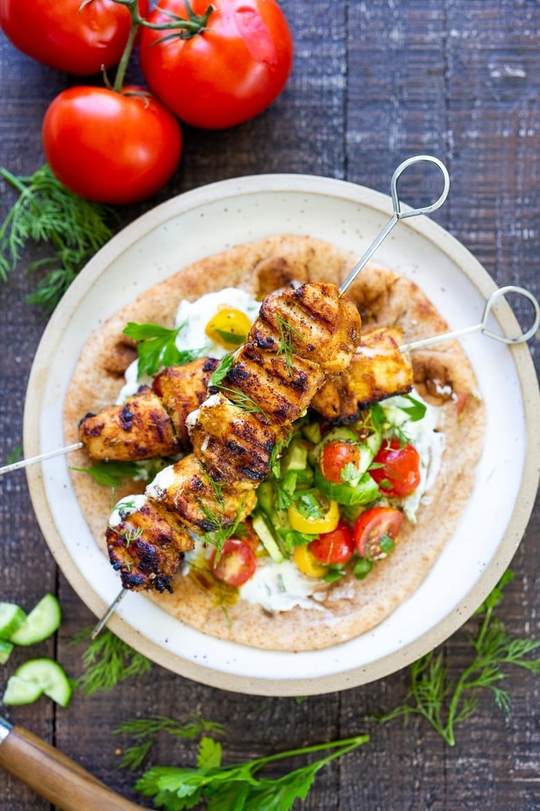 This EASY Grilled Chicken Shawarma skewers in a pita with tzatziki and tomatoes, cucumber and red onion.