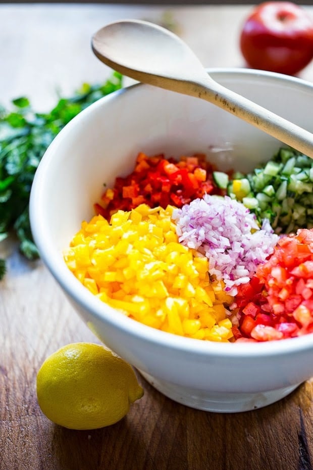 A simple & delicious recipe for Israeli Salad, made with finely chopped vegetables, fresh herbs, lemon and olive oil. Vegan and Gluten Free! | www.feastingathome.com