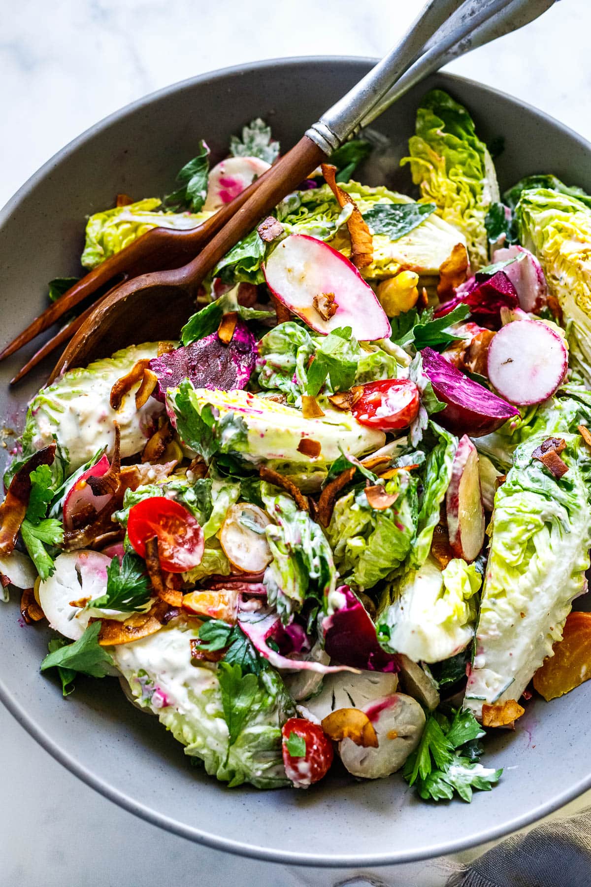 Cool and crisp Wedge Salad with little gems, beets, tomatoes, radishes, herbs and coconut bacon, topped with Creamy Gorgonzola dressing. 