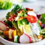 Cool and crisp Wedge Salad with little gems, beets, tomatoes, radishes, herbs and coconut bacon, topped with Creamy Gorgonzola dressing. 