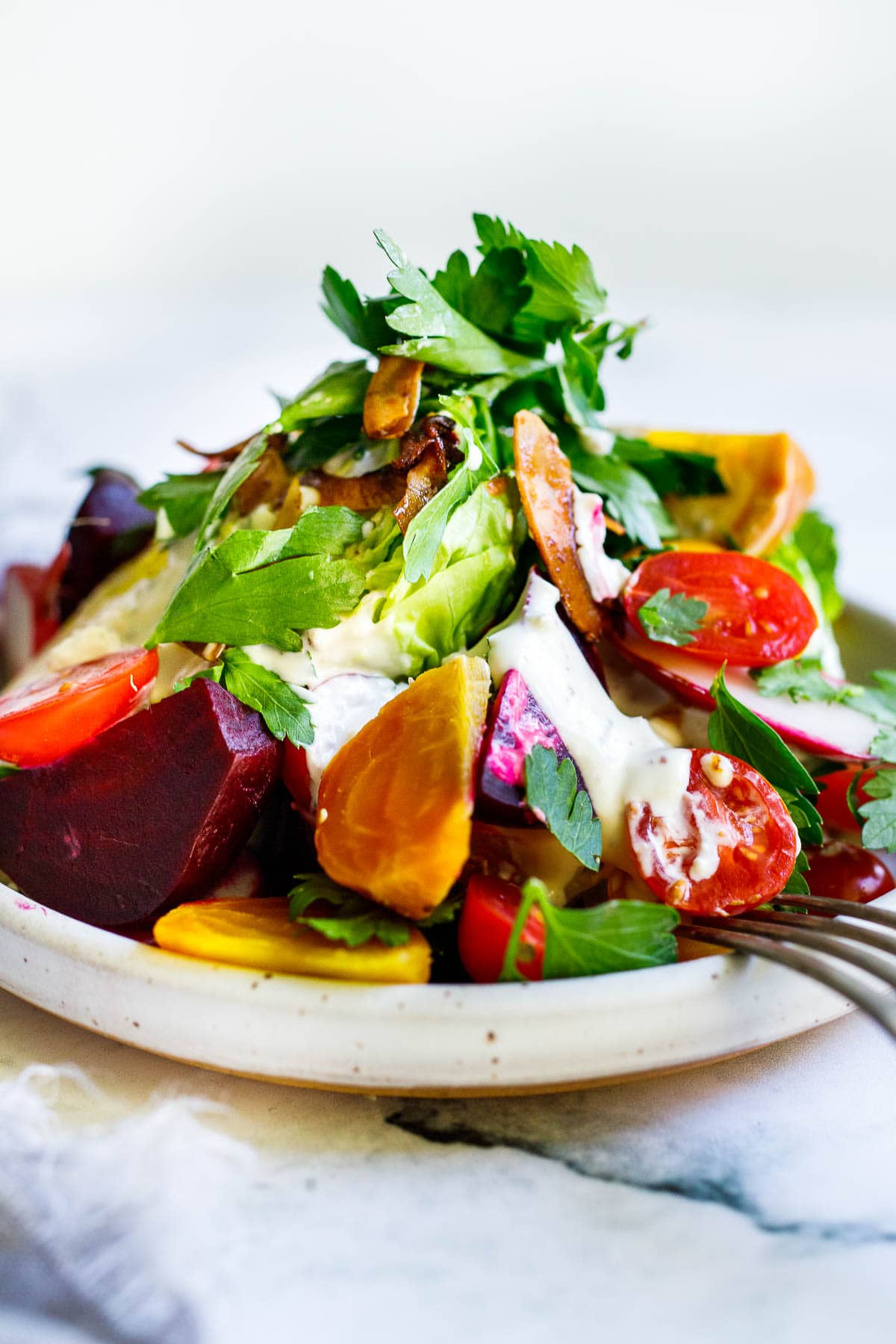 Cool and crisp Wedge Salad with little gems, beets, tomatoes, radishes, herbs and coconut bacon, topped with Creamy Gorgonzola dressing. 